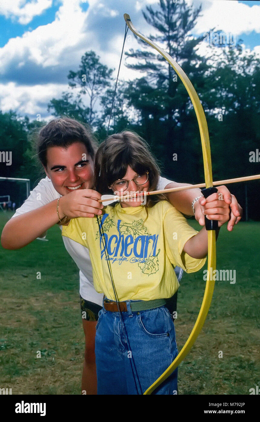 Une jeune fille reçoit une leçon dans le sport du tir à l'arc de son conseiller à un camp d'été à New York, United States, Amérique du Nord. Banque D'Images