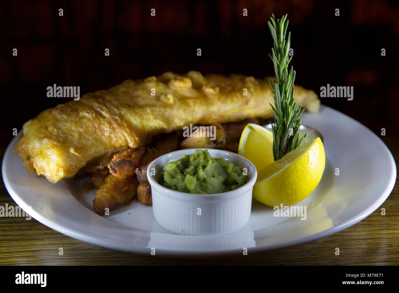Fish and Chips servis sur une plaque à Sunderland, en Angleterre. Le plat est servi avec un bol de petits pois et d'un morceau de citron. Banque D'Images