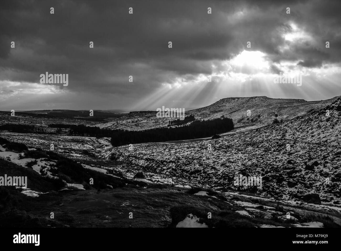 Rayons venant à travers les nuages sur un jour de neige, Burbage, Peak District Banque D'Images
