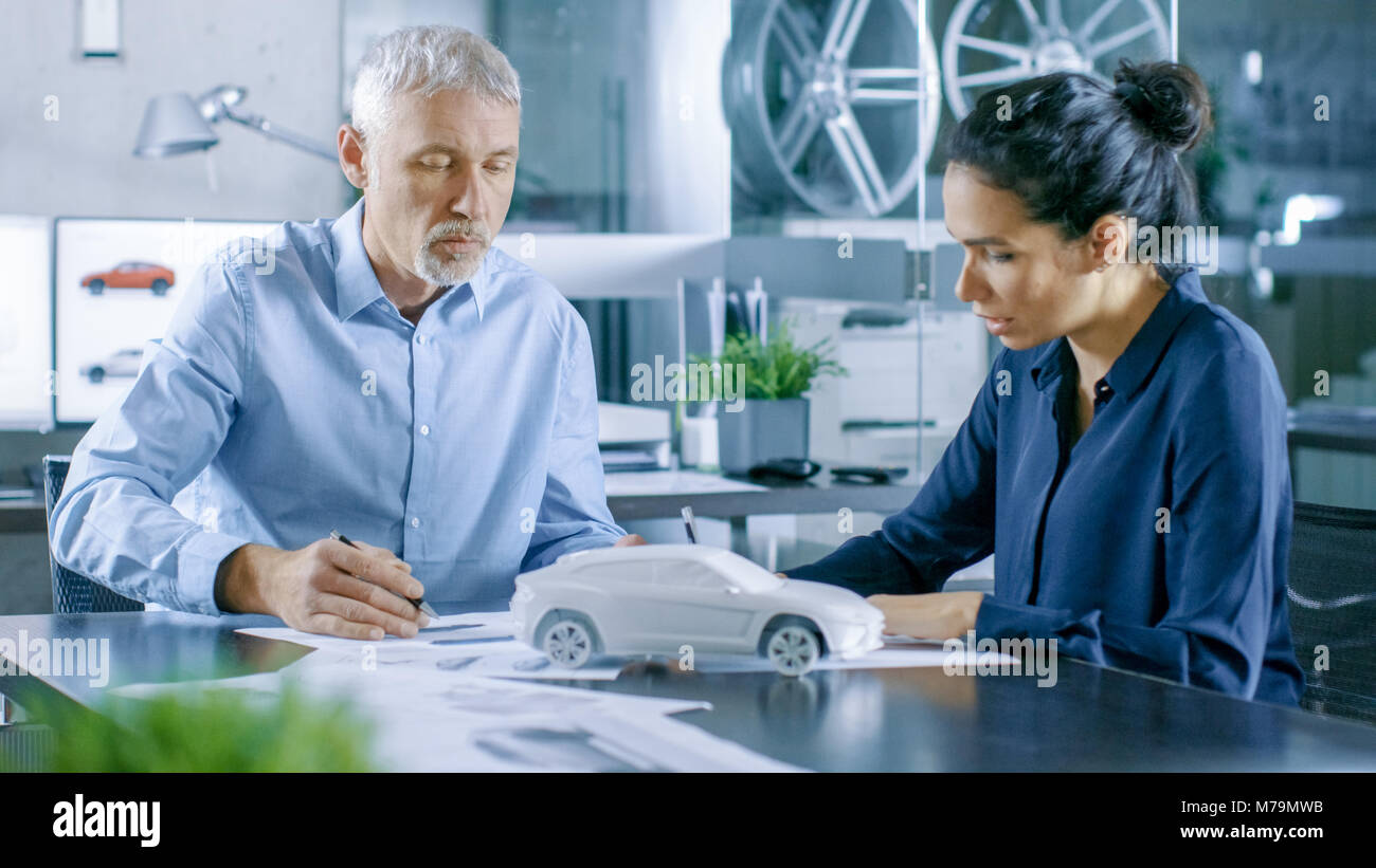 Designer automobile expérimenté et ingénieur femelle travaille avec des plans et des esquisses d'une nouvelle voiture Prototype. Banque D'Images