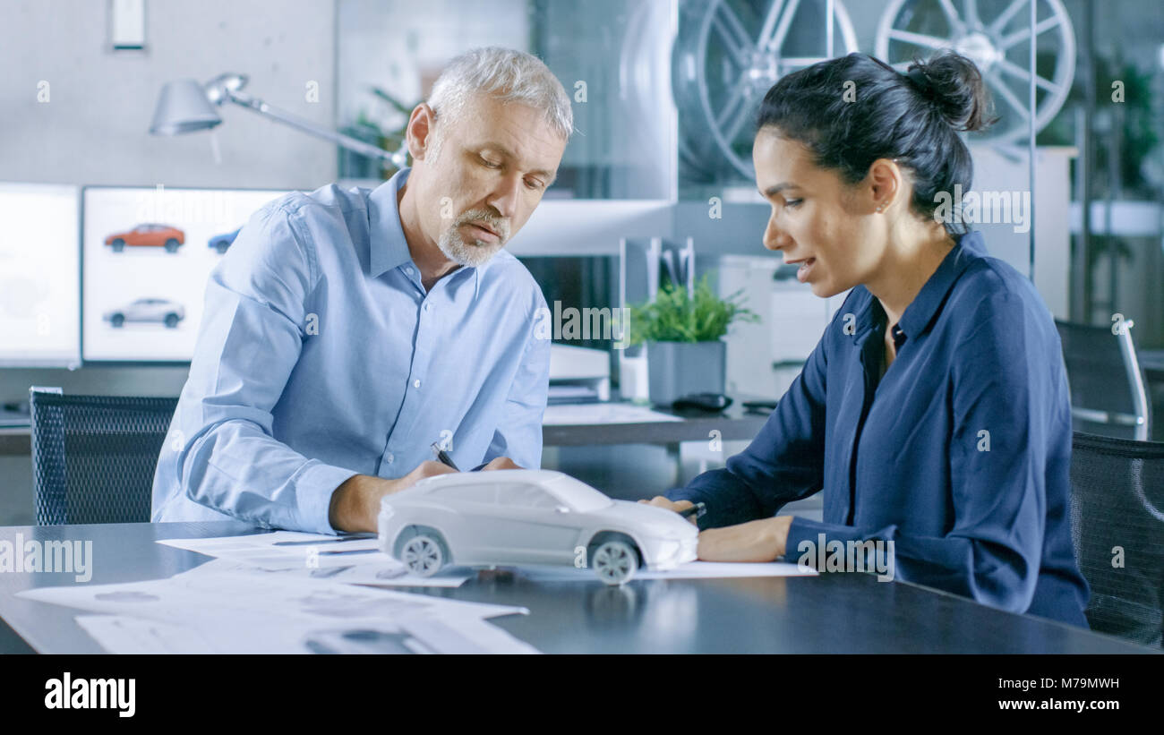 Designer automobile expérimenté et ingénieur femelle travaille avec des plans et des esquisses d'une nouvelle voiture Prototype. Banque D'Images