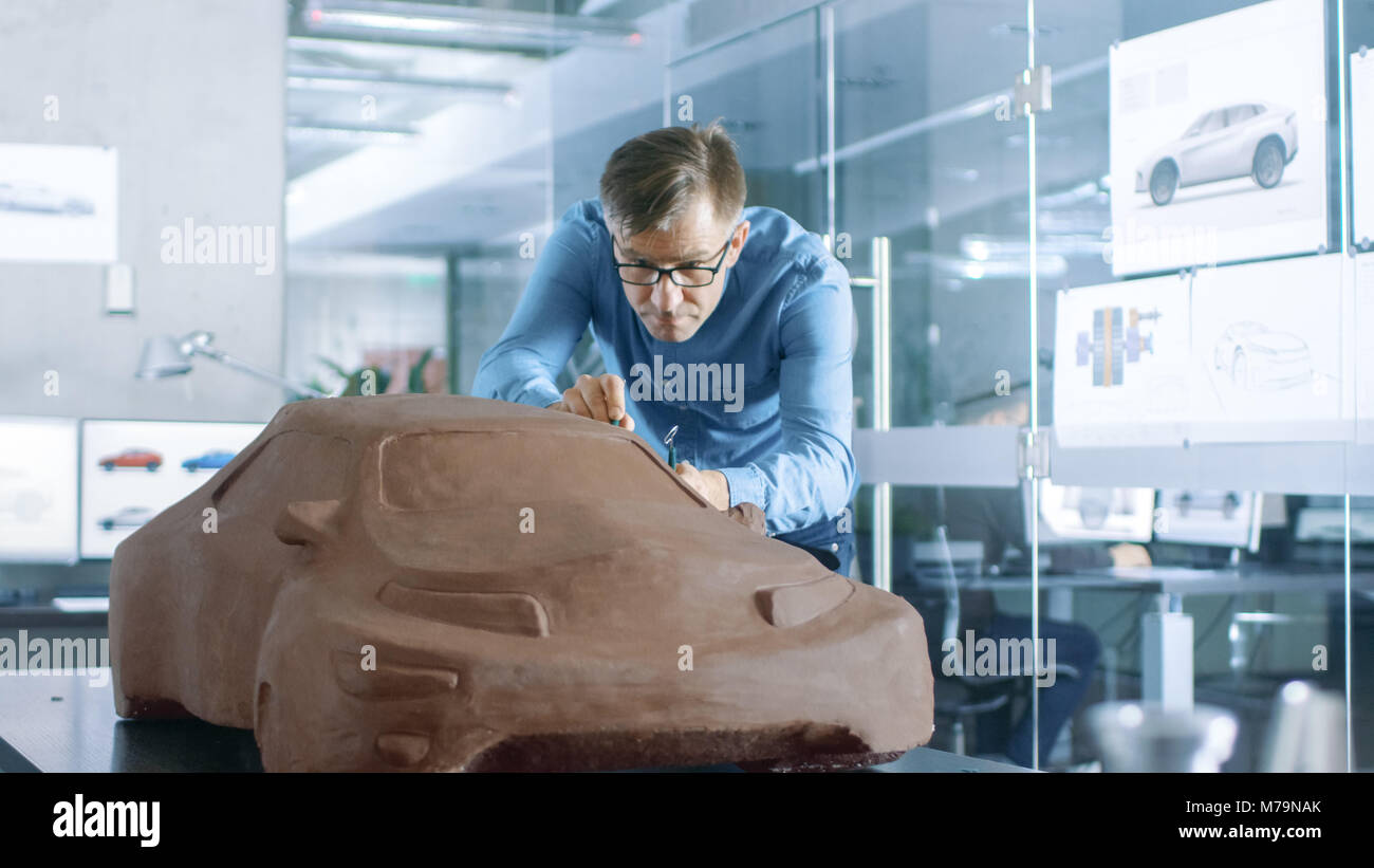 Designer automobile expérience avec un râteau sculpte modèle prototype de voiture à partir de la pâte à modeler l'argile. Il travaille dans un studio moderne dans une grande entreprise automobile Banque D'Images