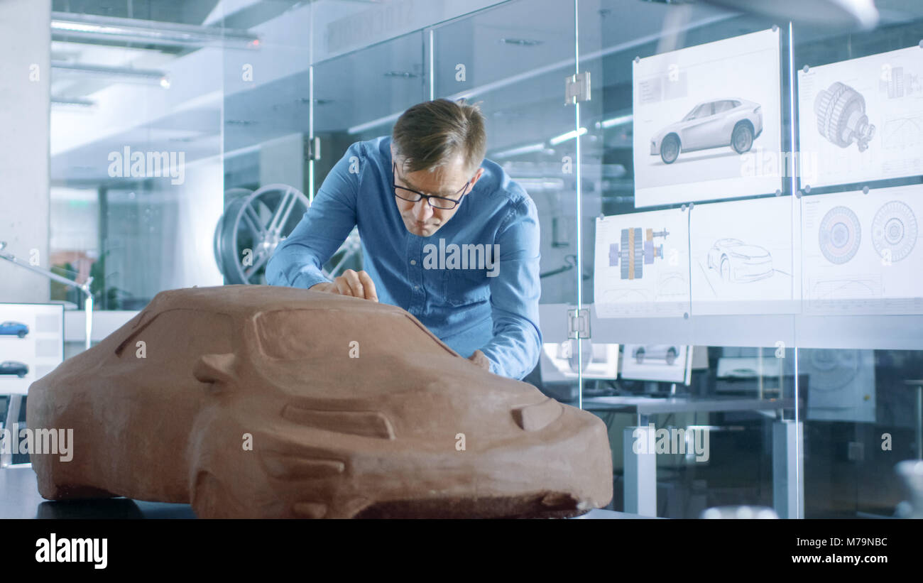 Designer automobile expérience avec un râteau sculpte modèle prototype de voiture à partir de la pâte à modeler l'argile. Il travaille dans un studio moderne dans une grande entreprise automobile Banque D'Images