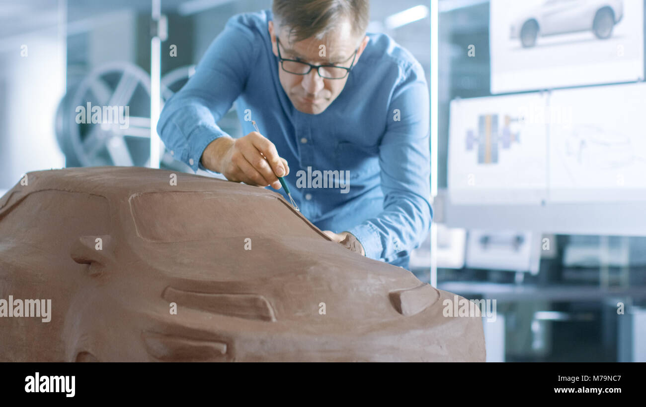 Designer automobile expérience avec un râteau sculpte modèle prototype de voiture à partir de la pâte à modeler l'argile. Il travaille dans un studio moderne dans une grande entreprise automobile Banque D'Images