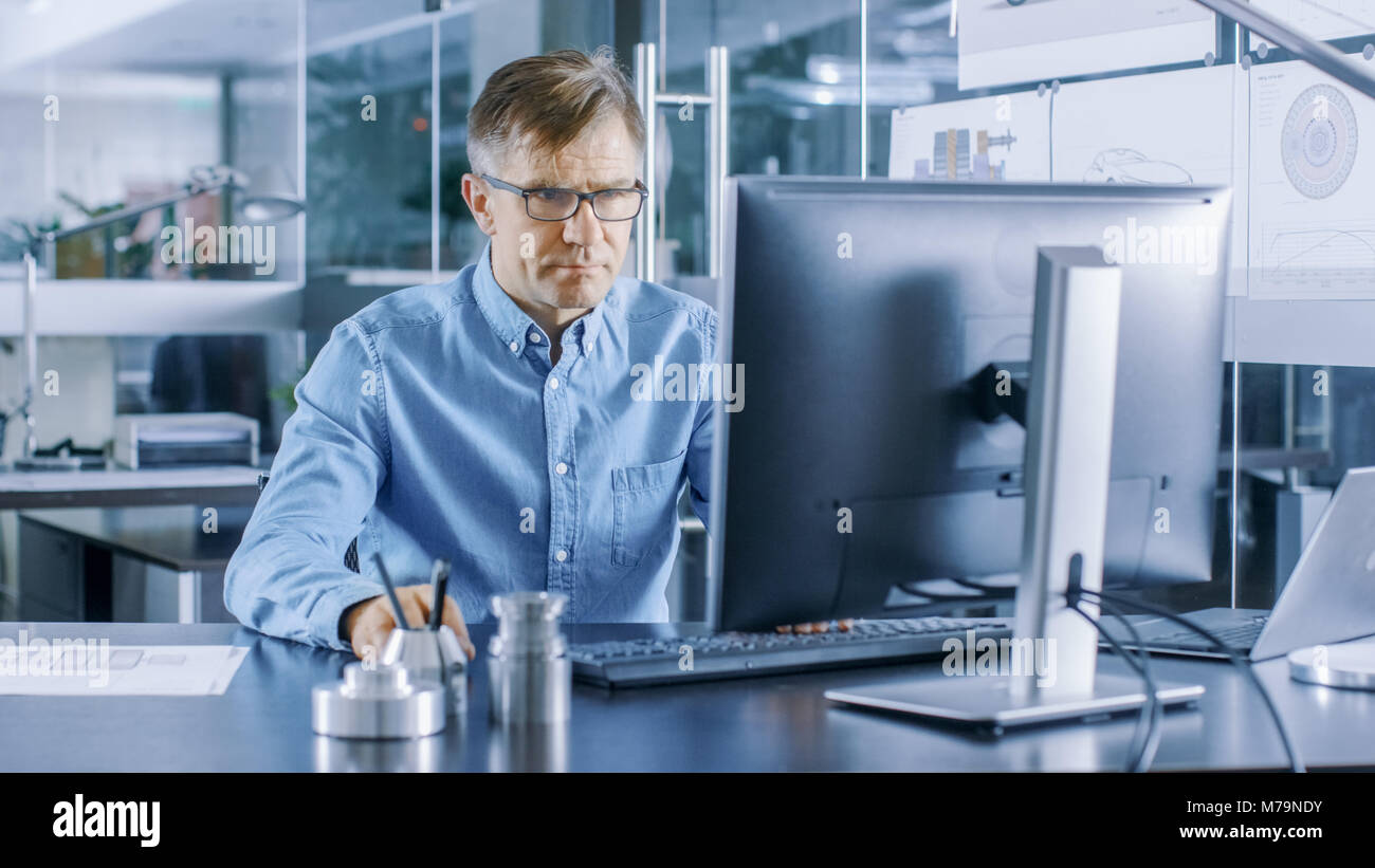 Ingénieur industriel expérimenté travaillant sur ordinateur personnel dans l'élégant, moderne, bureau en verre. Banque D'Images