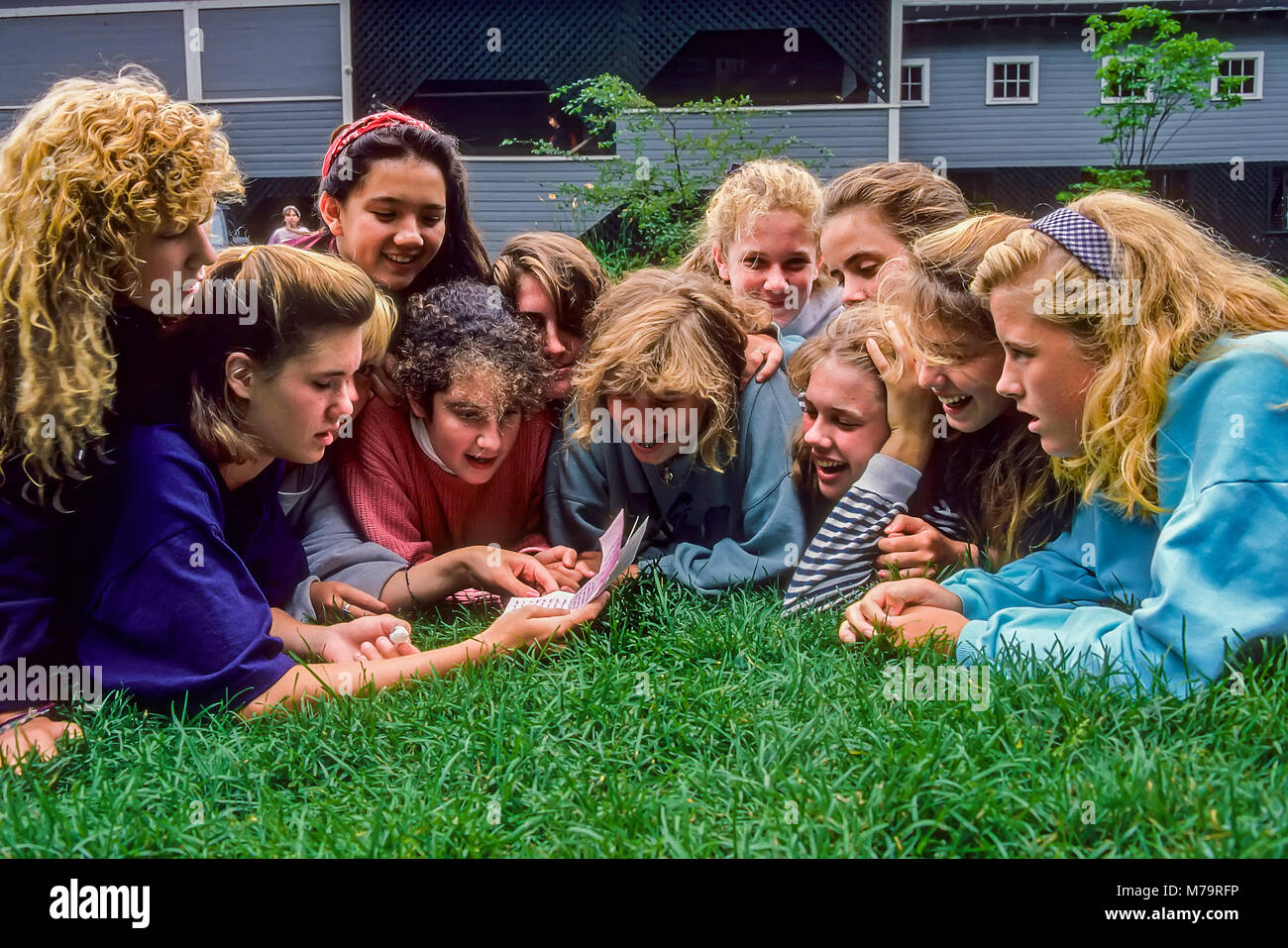 Un groupe de 11 jeunes filles au camp d'été étendu sur le sol en même temps la lecture de lettres d'accueil dans le Vermont, USA. Banque D'Images