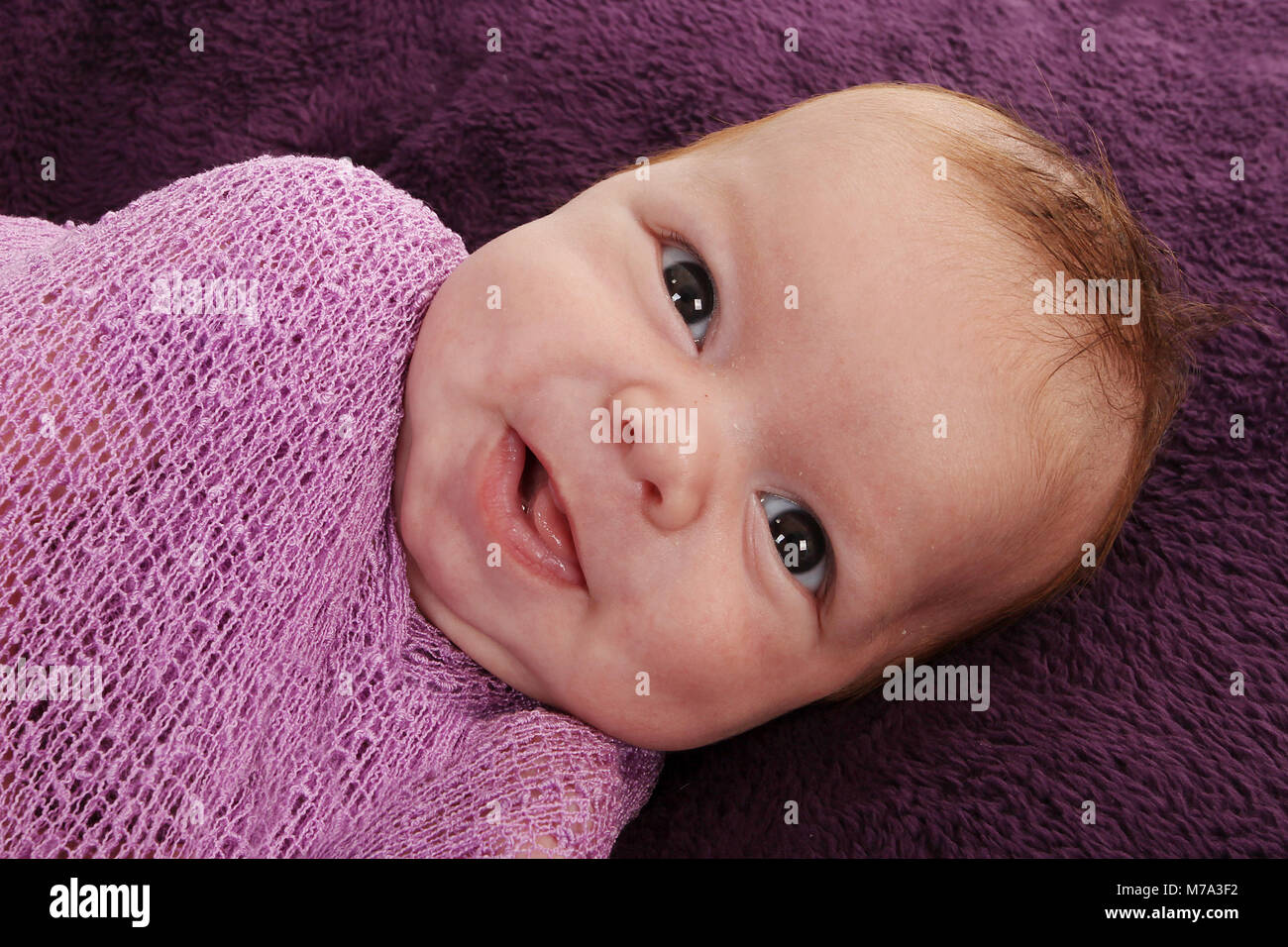 Bébé nouveau-né garçon heureux et confutable, emmailloté dans la douce couverture en pépinière, bébé emmailloté dans Banque D'Images