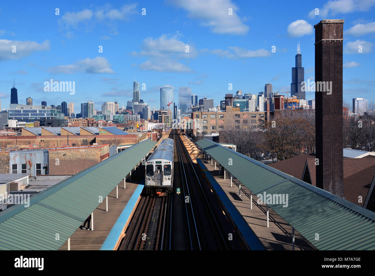 Un train de la ligne verte en direction ouest sur le lac Saint-Jean des pistes à la station Ashland avec l'horizon de Chicago s'étend à travers l'horizon. Banque D'Images