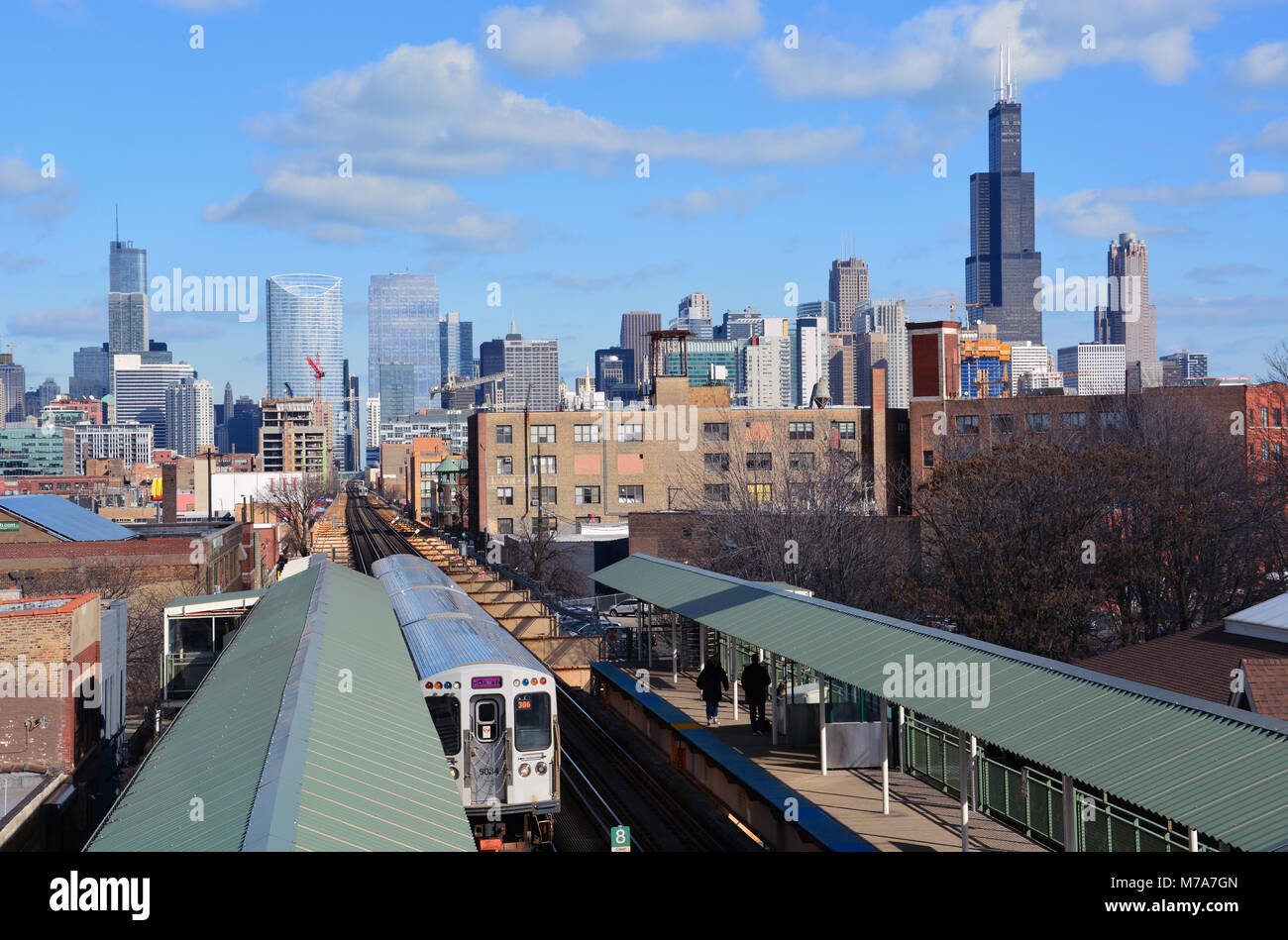 Une ligne rose train en direction ouest sur le lac Saint-Jean des pistes à la station Ashland avec l'horizon de Chicago s'étend à travers l'horizon. Banque D'Images