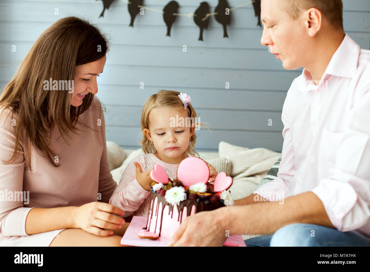 Les parents d'une petite fille. Girl essaie le gâteau avec son doigt Banque D'Images