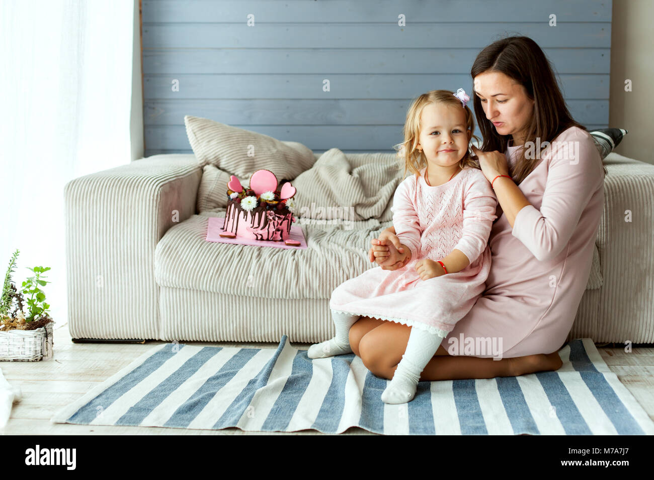 Petite fille avec sa mère et un gâteau d'anniversaire. Banque D'Images