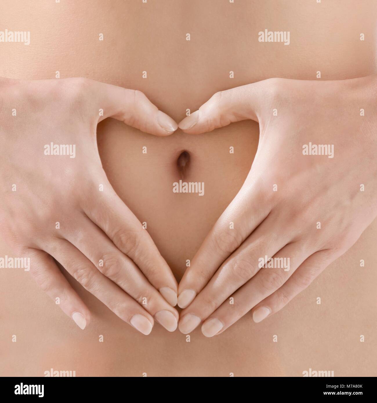 Woman making heart shape autour du nombril. Banque D'Images