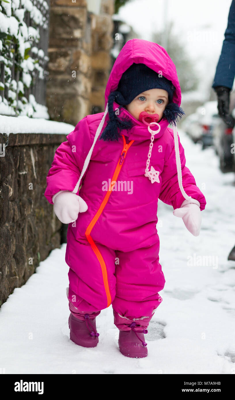 Adorable bébé enfant fille dans un costume de neige magenta jouant sur la neige. Banque D'Images