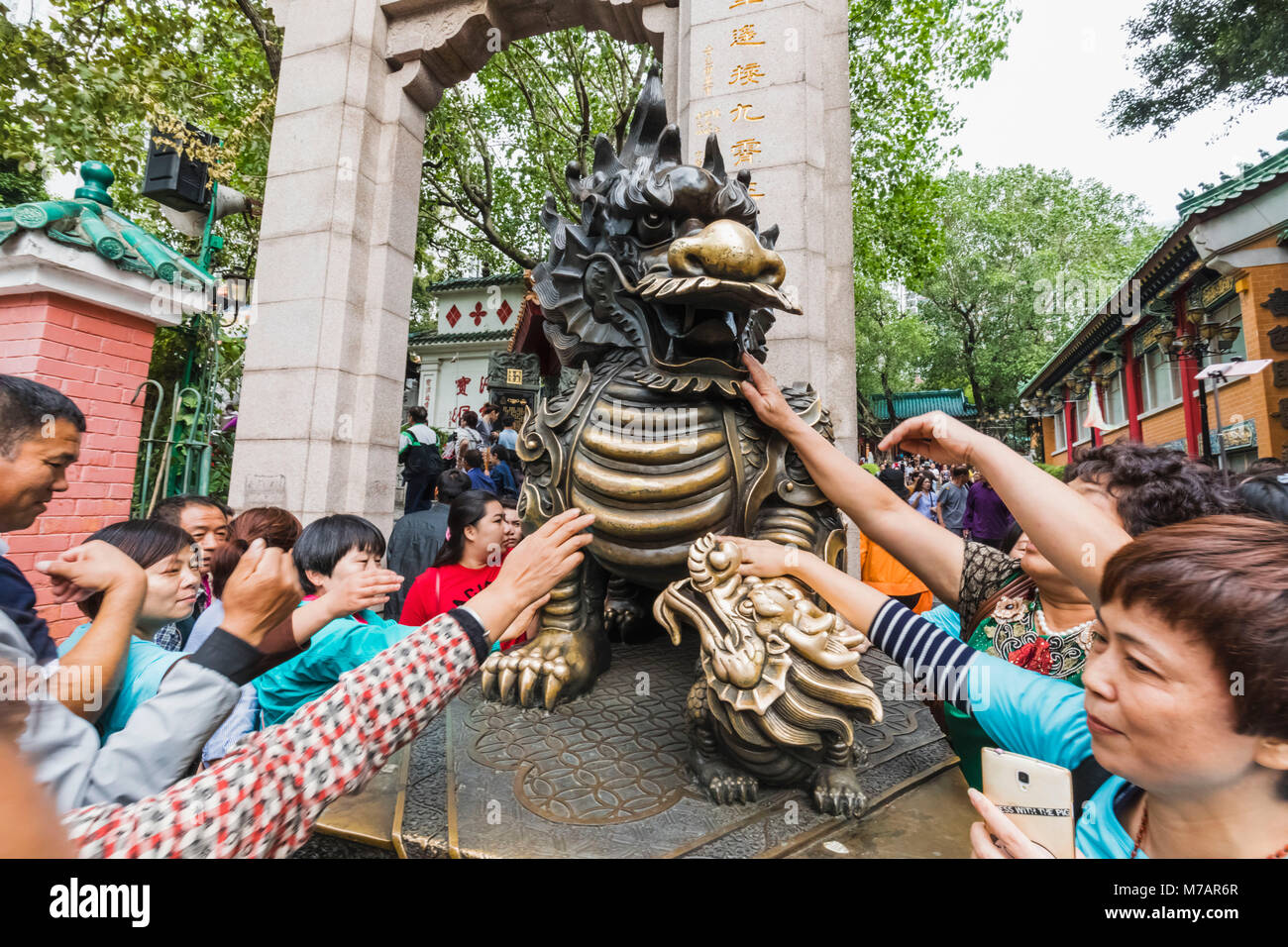 La Chine, Hong Kong, Kowloon, Sai Wong Tin Temple, toucher les touristes chinois Dragon Statue pour la bonne chance Banque D'Images