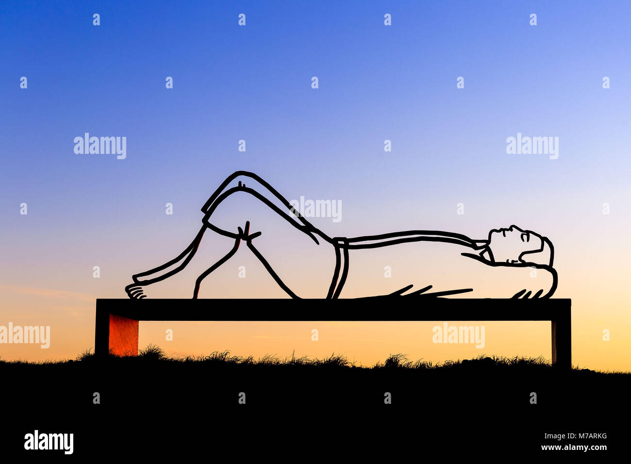 L'homme couché sur un banc au coucher du soleil Banque D'Images