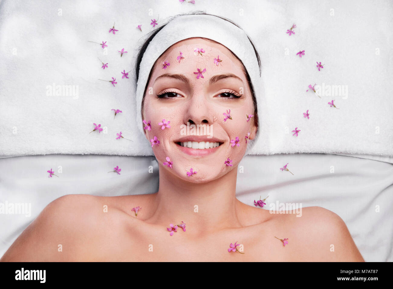 Femme au visage pack et des fleurs sur son visage Banque D'Images