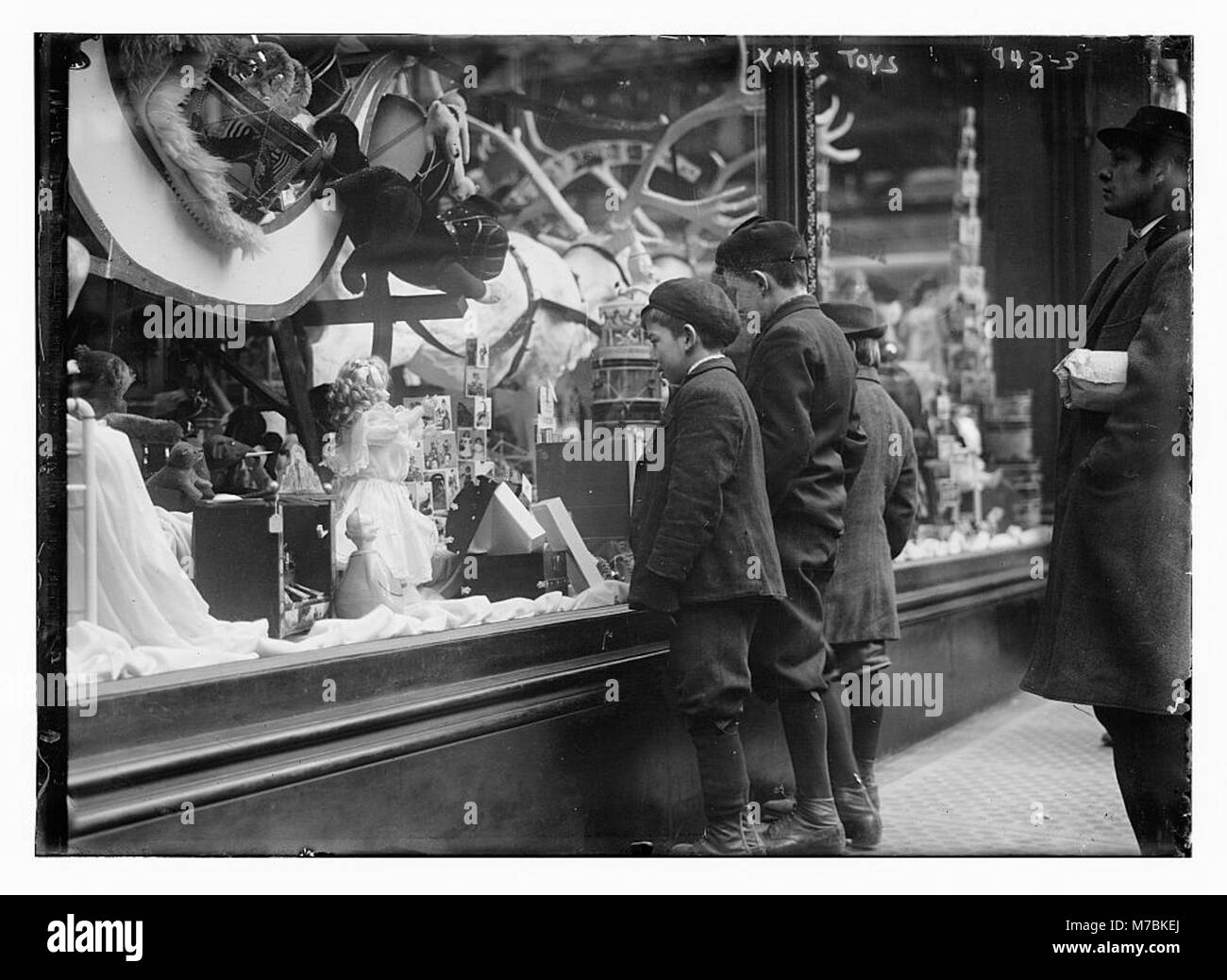 Les enfants sont vus contempler les jouets de Noël exposés dans une vitrine, capturant un moment festif d'anticipation et d'excitation des vacances. Banque D'Images