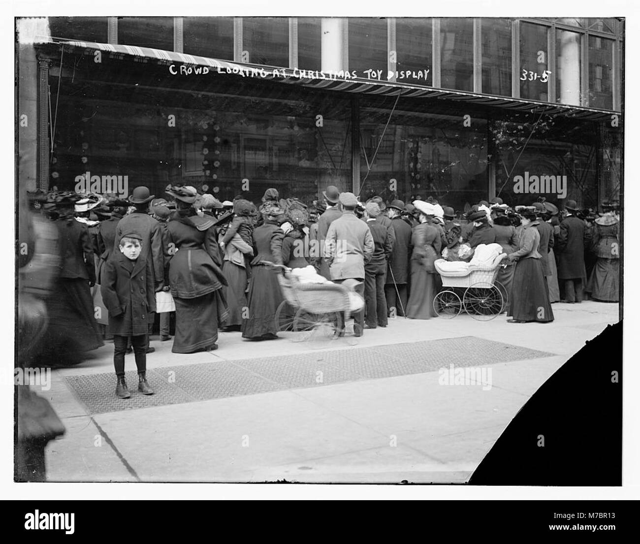 Une photographie représentant une foule réunie autour d'un présentoir de jouets de Noël, mettant en évidence les achats de vacances et les décorations festives. Banque D'Images