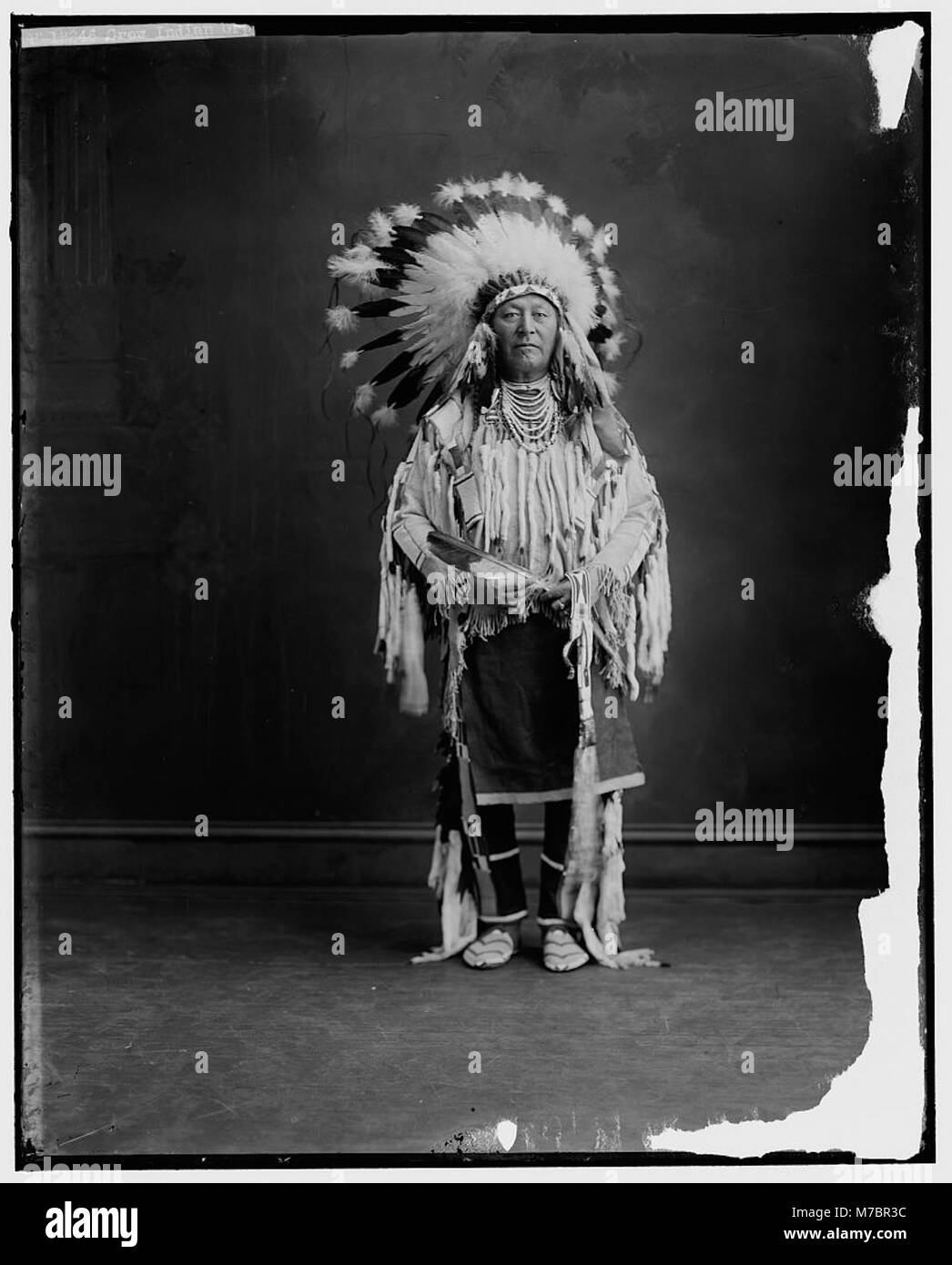 Photographie d'un Indien Crow, capturant l'individu dans une tenue traditionnelle. L'image reflète l'héritage culturel du peuple du Crow et l'histoire plus large des tribus amérindiennes. Banque D'Images Photographie d'un Indien Crow, capturant l'individu dans une tenue traditionnelle. L'image reflète l'héritage culturel du peuple du Crow et l'histoire plus large des tribus amérindiennes. Banque D'Images