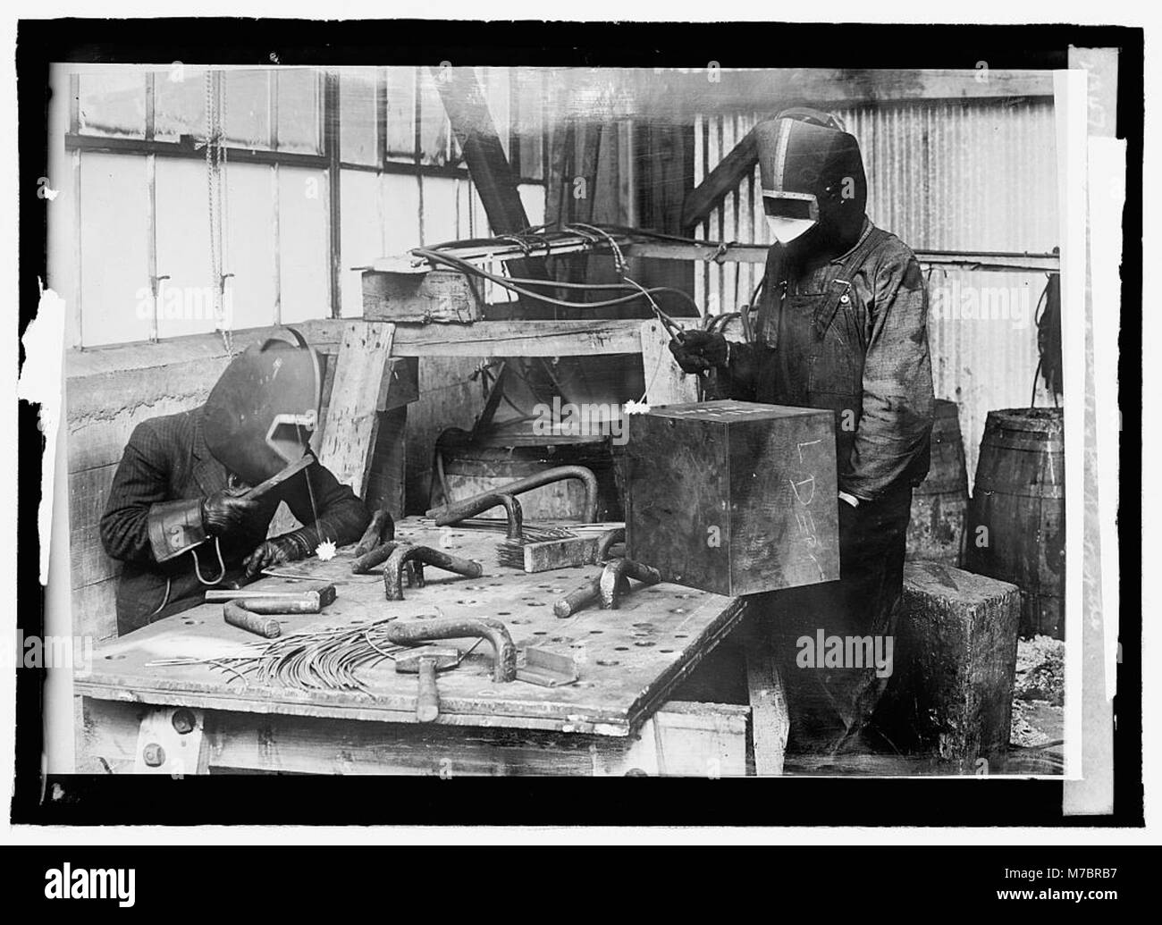 Un ouvrier utilise un outil d'oxycoupage à l'acétylène, avec des masques de protection et des lunettes de verre bleu pour protéger les yeux de la lumière intense et de la chaleur, assurant la sécurité pendant l'opération. Banque D'Images