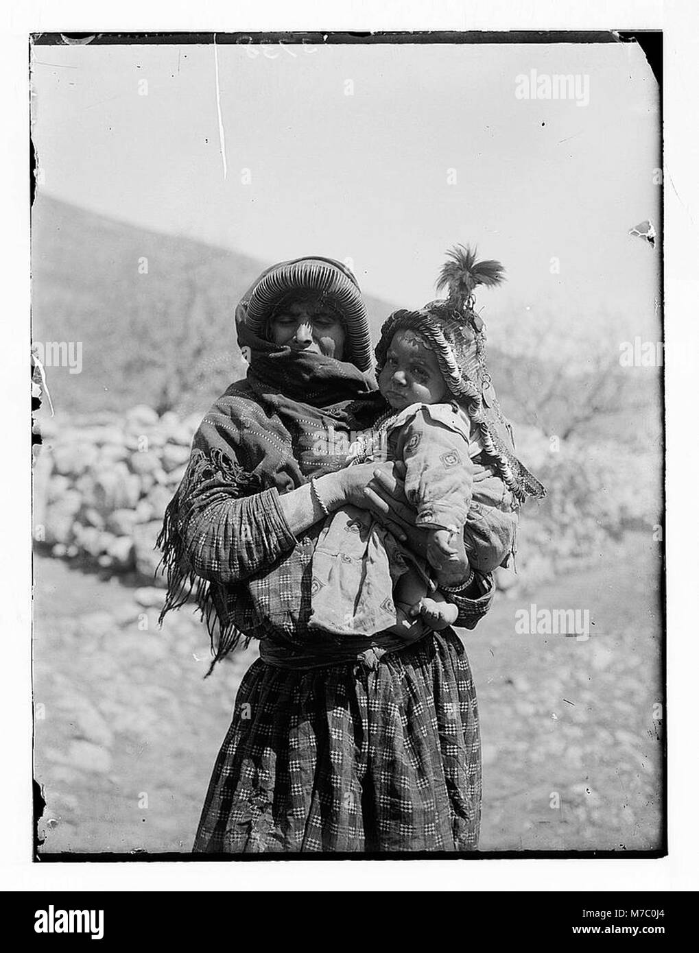 Photographie d’une femme arabe tenant son enfant, capturant un moment familial dans un contexte culturel du début du XXe siècle. Banque D'Images