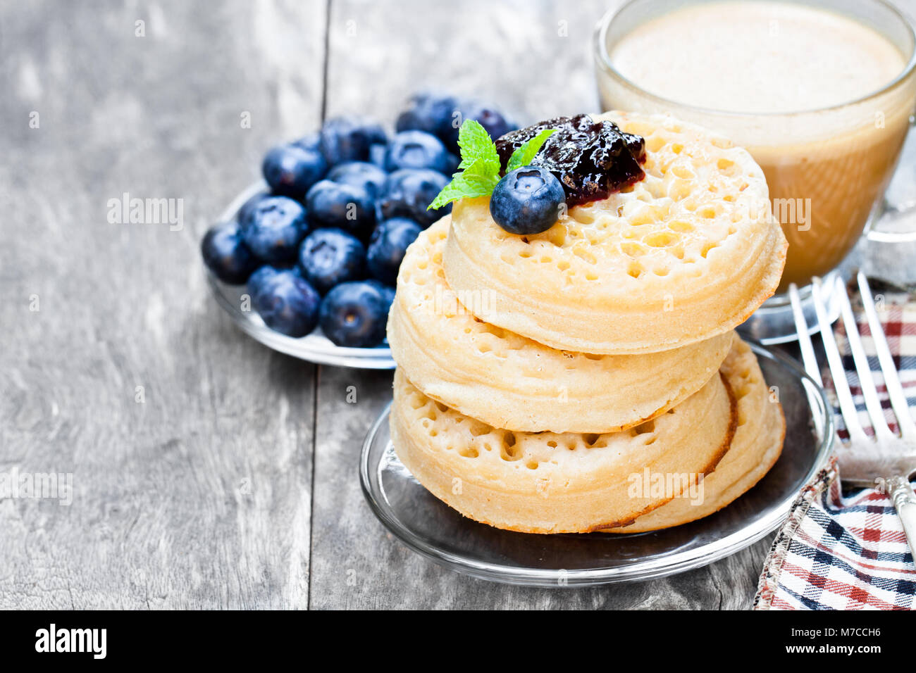 Sex crumpets grillés sur la table en bois avec des bleuets et de la confiture Banque D'Images