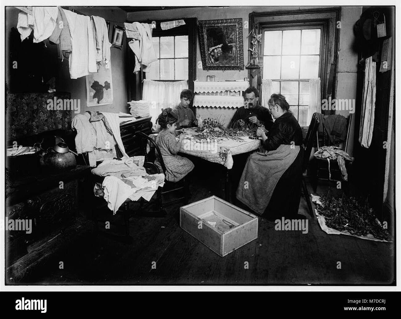 Une jeune fille de six ans nommée Julin qui pansionne ses voisins au dernier étage du 106 Thompson Street à New York. L'image la capture créant de petites fleurs pour d'autres, avec mention d'un growler et de bière à proximité. Banque D'Images