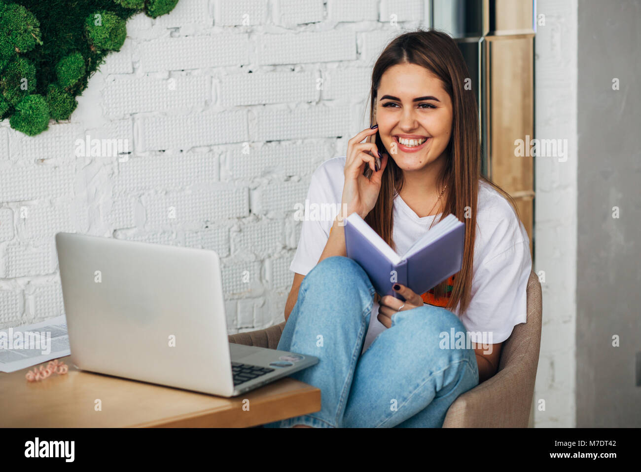 Une jeune fille est un indépendant travaillant dans le café avec un ordinateur portable et smiling at camera Banque D'Images
