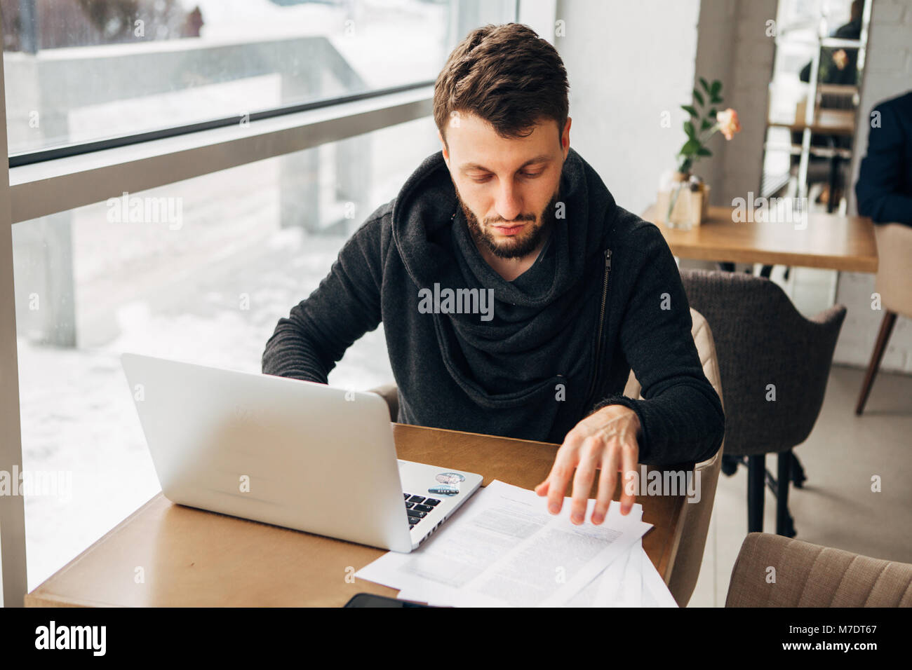 Un jeune homme travaille dans un café avec un ordinateur portable Banque D'Images