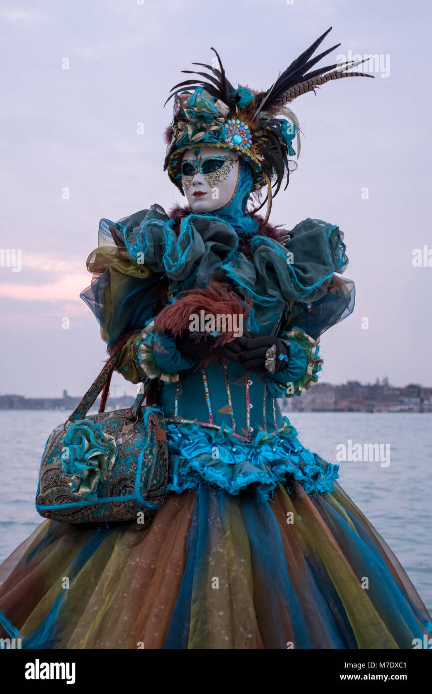 Femme en costume, chapeau à plumes et le masque, photographié au cours du  San Giorgio pendant le carnaval vénitien (Carnaval de Venise) au crépuscule  Photo Stock - Alamy