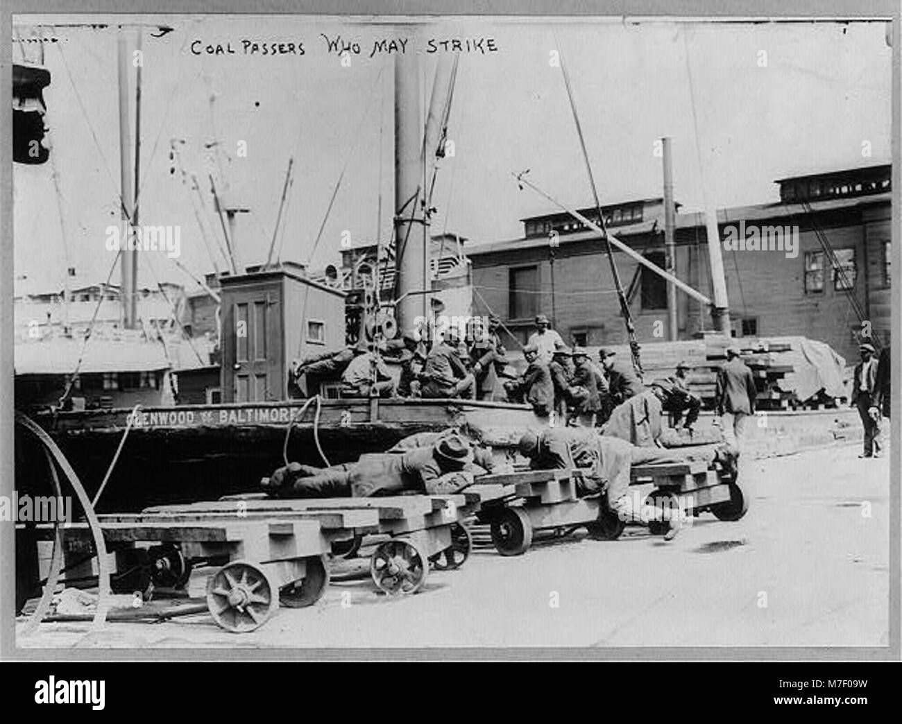 Une image représentant des passants du charbon dans une grève des marins, mettant en évidence les troubles du travail parmi les travailleurs maritimes. La photographie reflète les conditions industrielles tendues de l'époque. Banque D'Images