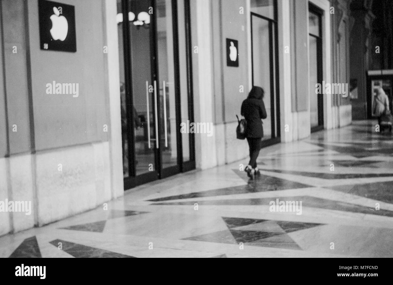 Jeune femme marchant devant l'Apple Store de la Piazza della Repubblica, Florence Italie Banque D'Images