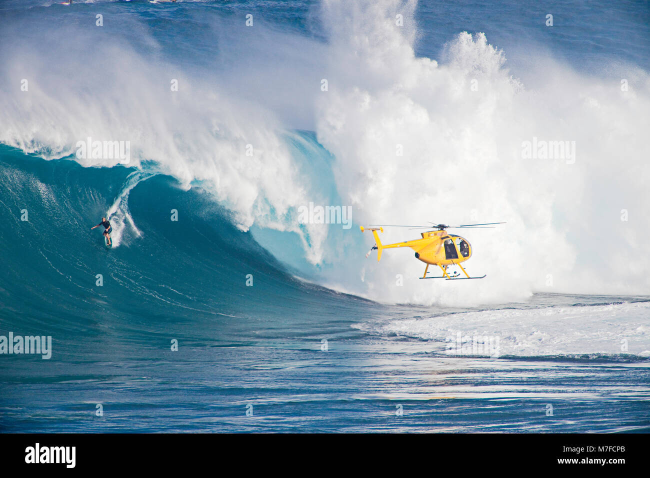 Un hélicoptère prend un tow-in à Peahi surfer (Mâchoires) au large de Maui. Hawaii. Banque D'Images