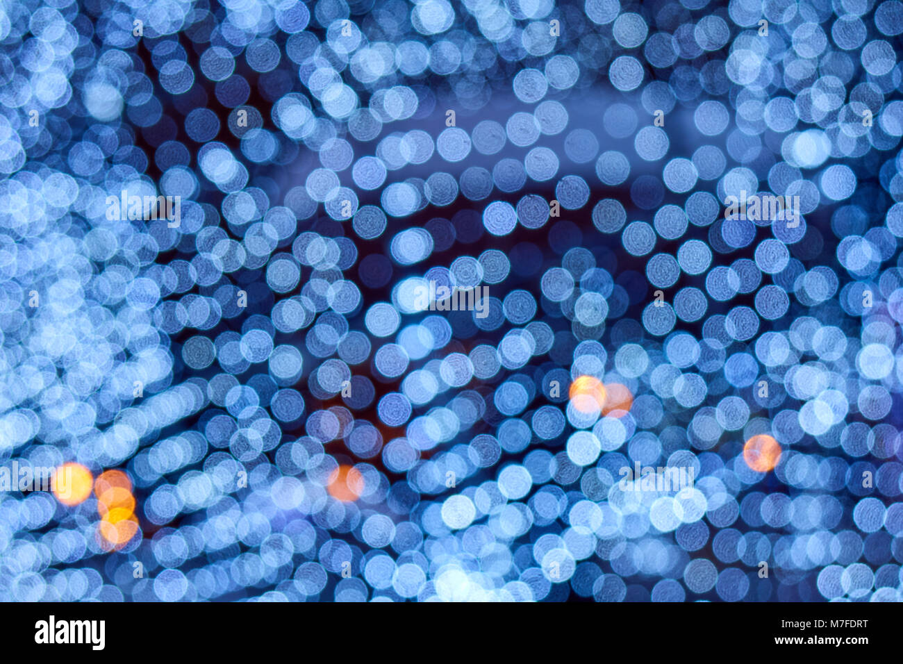 Arrière-plan flou bleu néon,, beaucoup de petits cercles bokeh avec quelques points orange, motif texture Banque D'Images