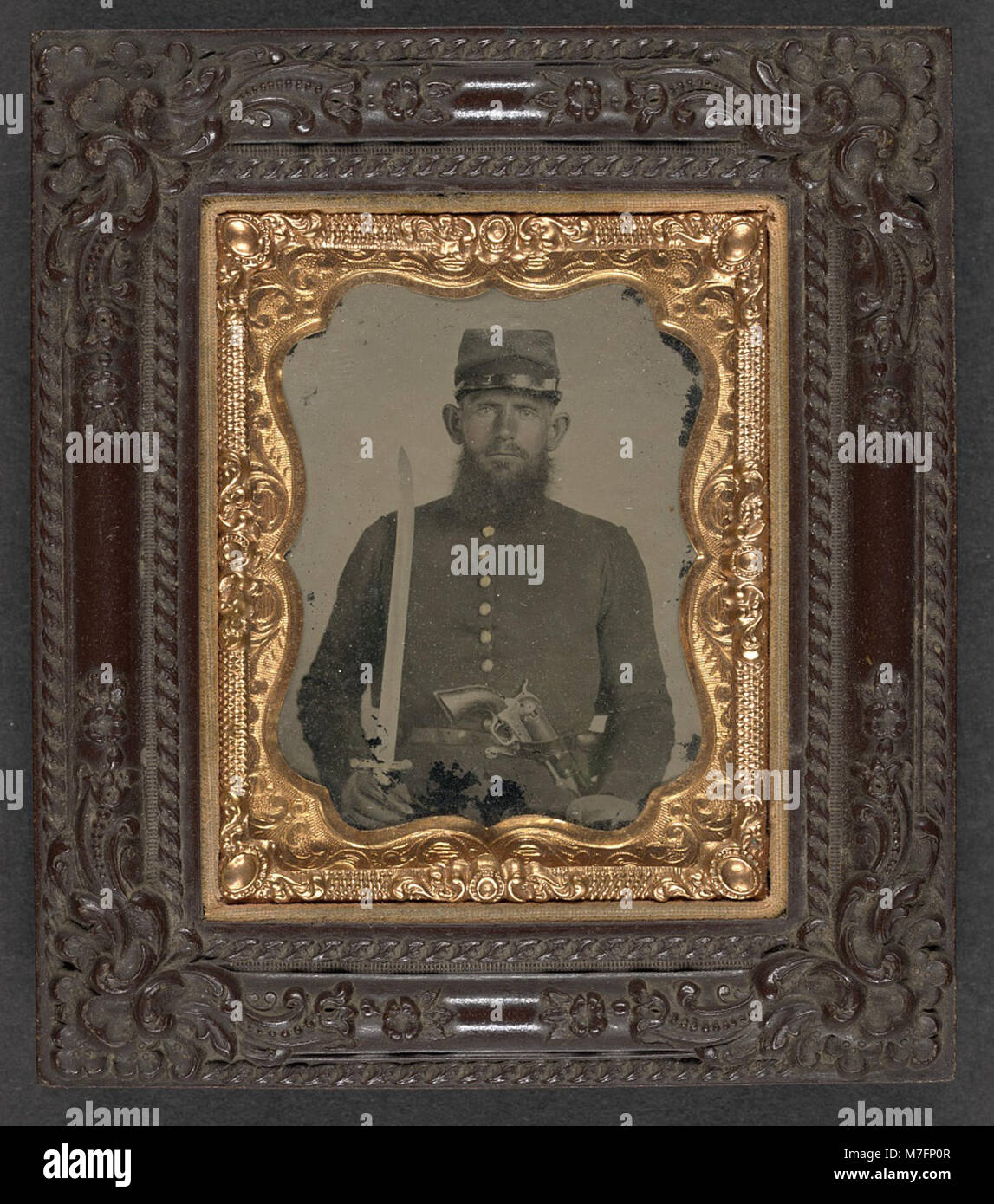 Une photographie d'un soldat de l'Union non identifié de la guerre de Sécession, tenant un revolver et une épée, vêtu d'un uniforme de l'Union, mettant en valeur la tenue militaire de l'époque. Banque D'Images