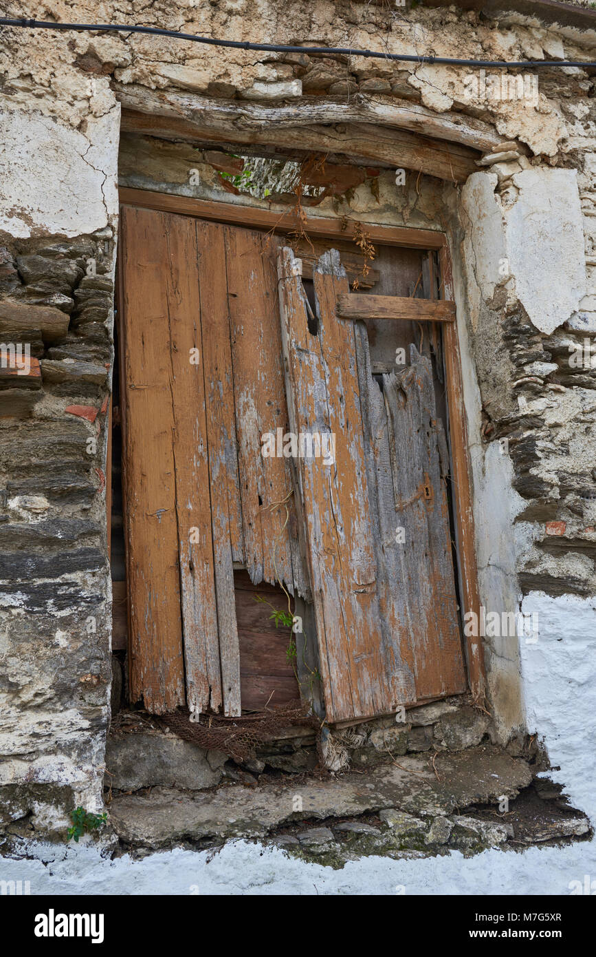 Une vieille porte en bois avec beaucoup de dommages visibles sur la face avant d'une maison abandonnée dans le village de Sayalonga en Andalousie, espagne. Banque D'Images