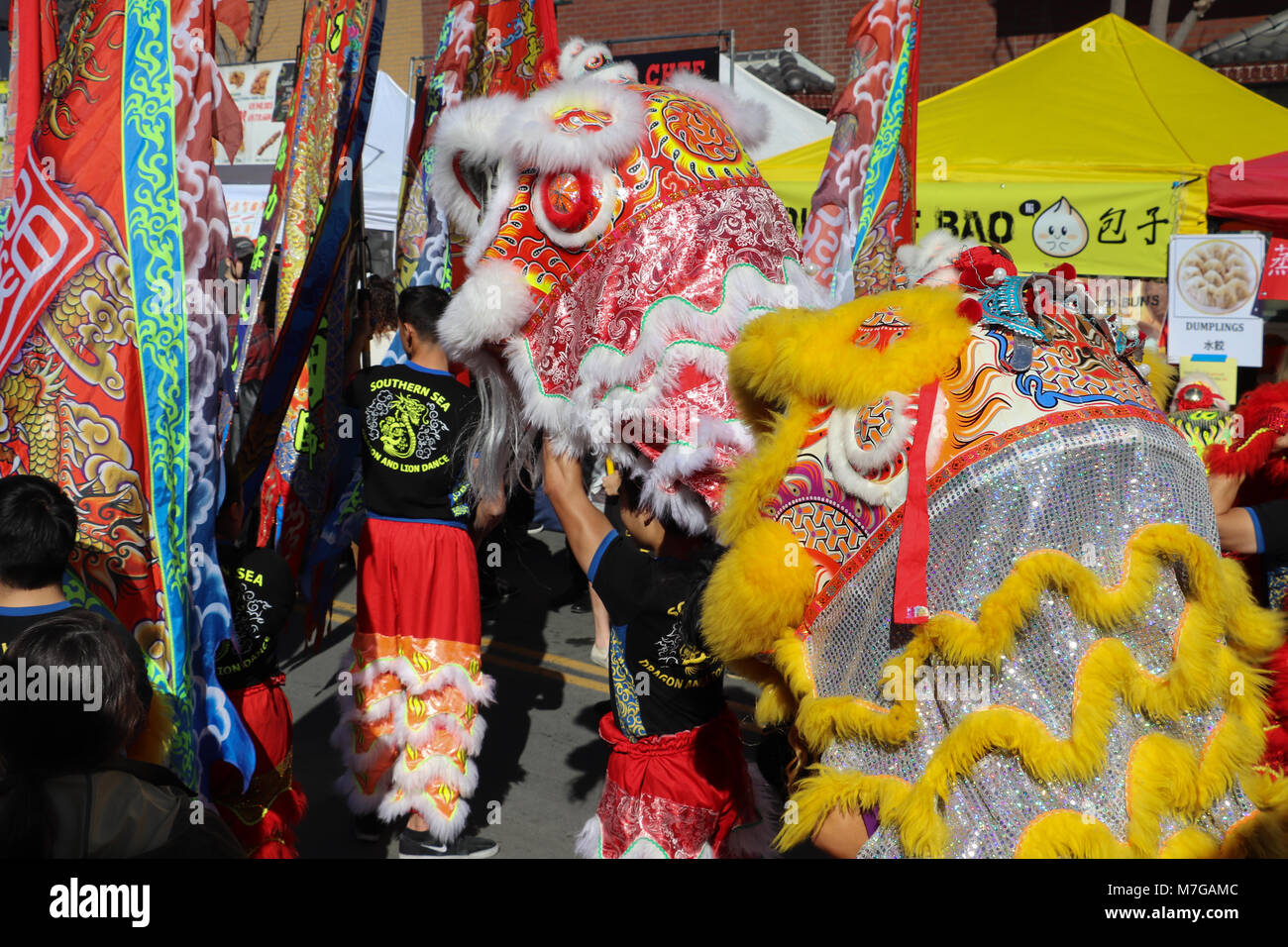 Les hommes portent des costumes et des bannières lion danse pendant un défilé du Nouvel An chinois colorés lors d'une foire de rue de San Diego tp célébrer la fête du printemps. Banque D'Images