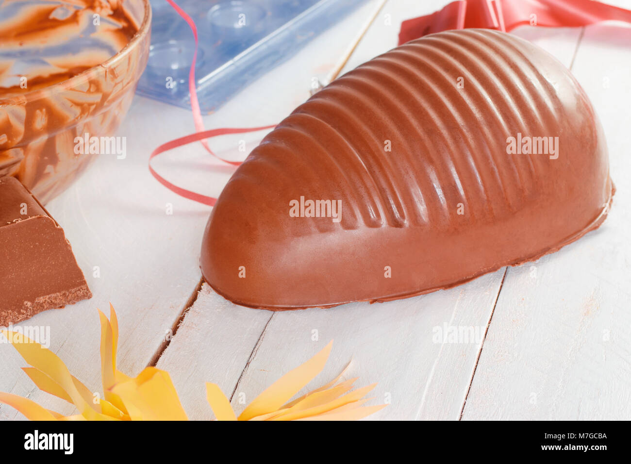 De pâques en chocolat, montrant un œuf en chocolat de la moitié, et pièce en salle, moules, avec des rubans décoratifs Banque D'Images