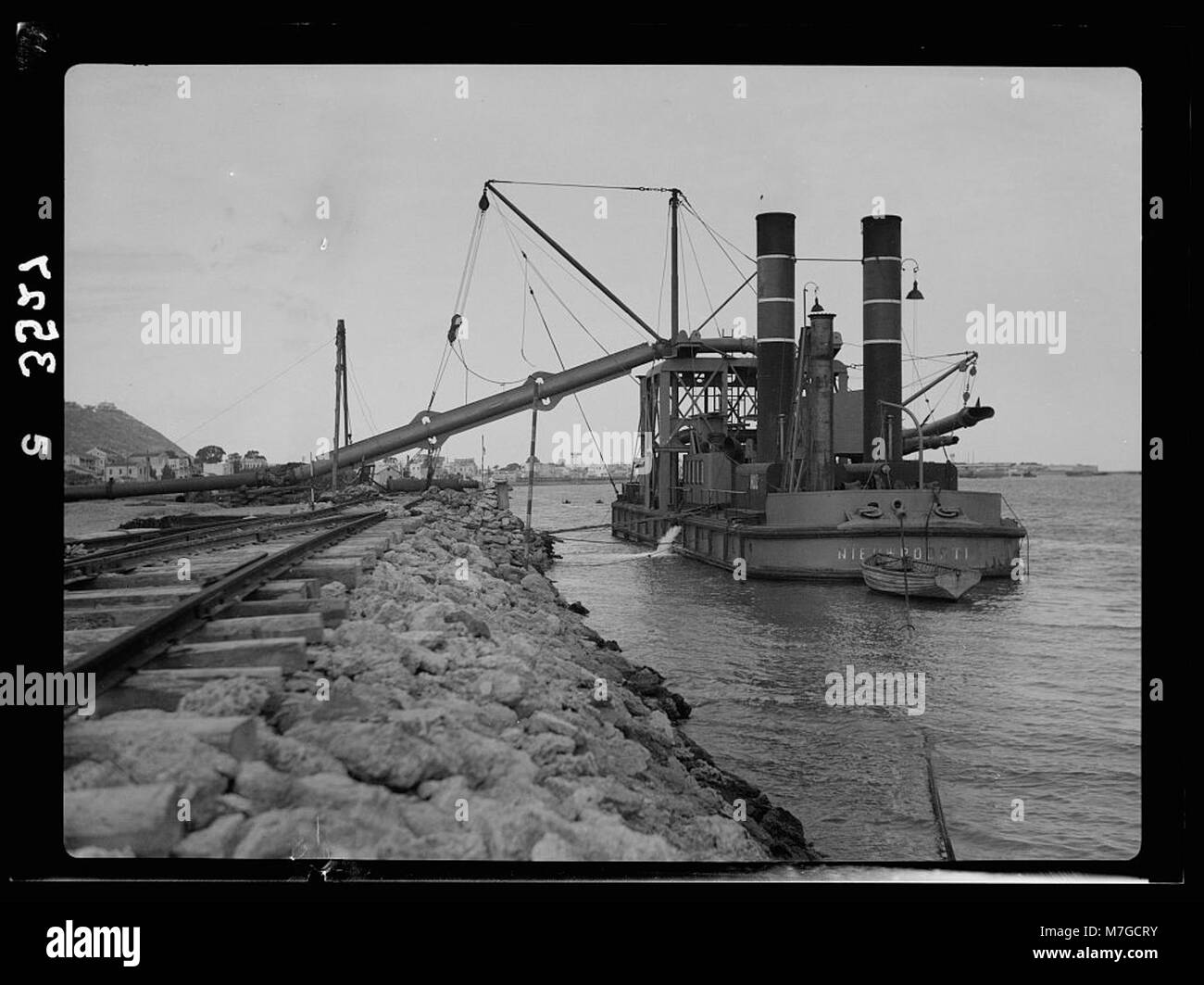 La construction du port de Haïfa impliquait l'utilisation d'une pompe à sable pour pomper le sable sur des terres récupérées. Ce processus était essentiel pour l'expansion du port et l'augmentation de sa capacité pour les activités maritimes. Banque D'Images