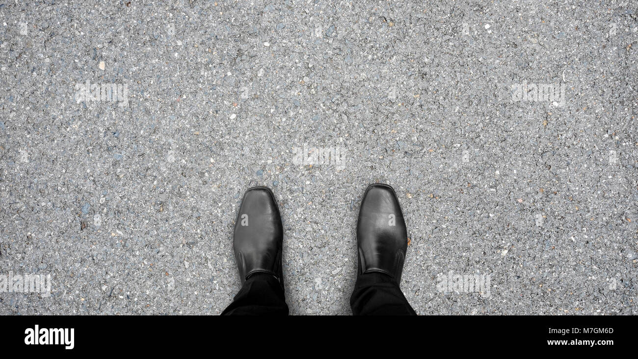 Chaussures noires debout sur le plancher de béton d'asphalte Banque D'Images
