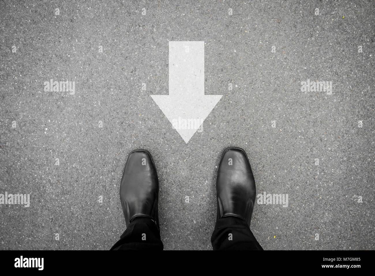Businessman in chaussures noires debout sur la route de béton bitumineux et de direction arrière. Mauvaise façon et avoir à revenir en arrière. Banque D'Images
