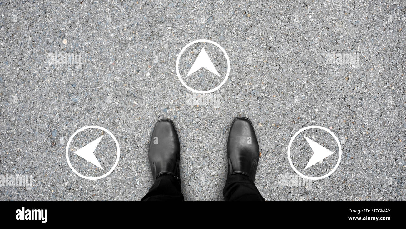 Chaussures noires debout à la croisée de décider où aller - trois façons de choisir. Rond blanc direction sur le sol en béton. Banque D'Images