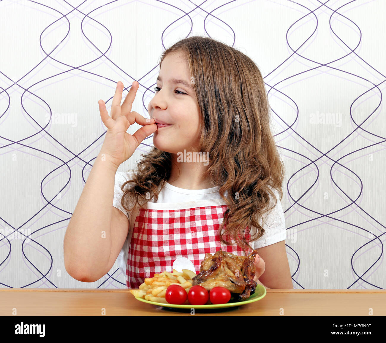 Happy little girl avec ailes de poulet rôties et ok part sign Banque D'Images