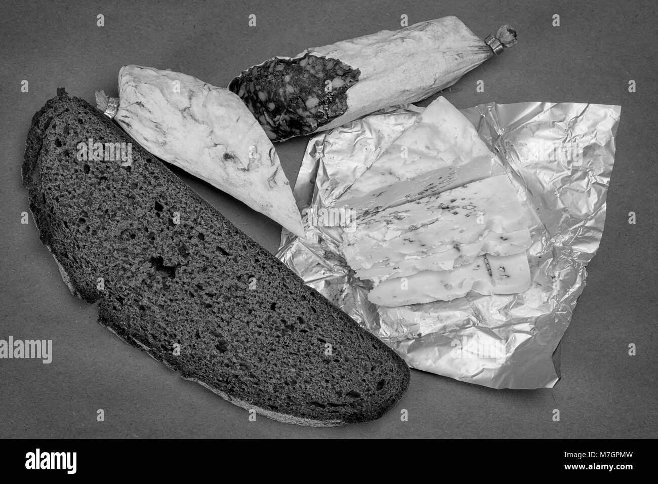Thème Le petit déjeuner nature morte. Pain, fromage Roquefort et saucisse fumée sur fond de papier craft. Photo en noir et blanc Banque D'Images