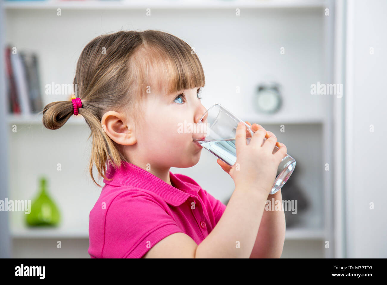 Enfant boit un verre d'eau du verre à la maison. Santé et beauté concept Banque D'Images