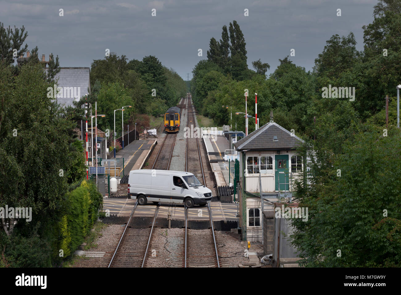 Un train part de Lowdham (à l'Est de Nottingham) comme trafic traverse le passage à niveau Banque D'Images