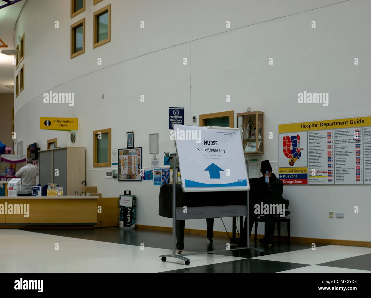 Un signe de recrutement de personnel infirmier s'affiche à côté d'un pianiste dans l'entrée principale de l'hôpital de Queen's à Romford, dans l'Est de Londres le 10 mars 2018. Banque D'Images