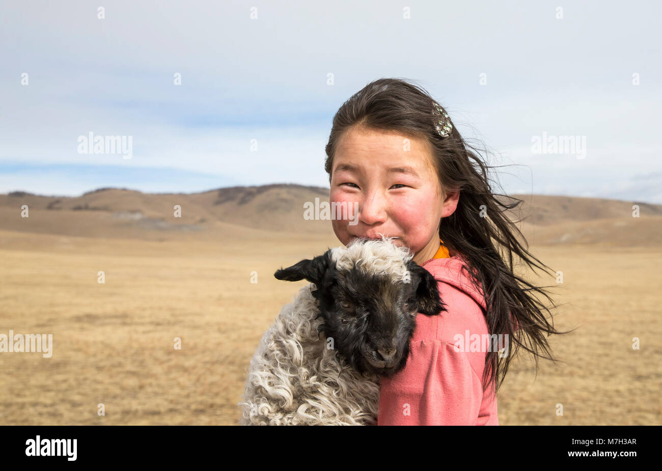 Hatgal, la Mongolie, le 2 mars 2018 : fille mongole portant un bébé mouton dans une steppe Banque D'Images