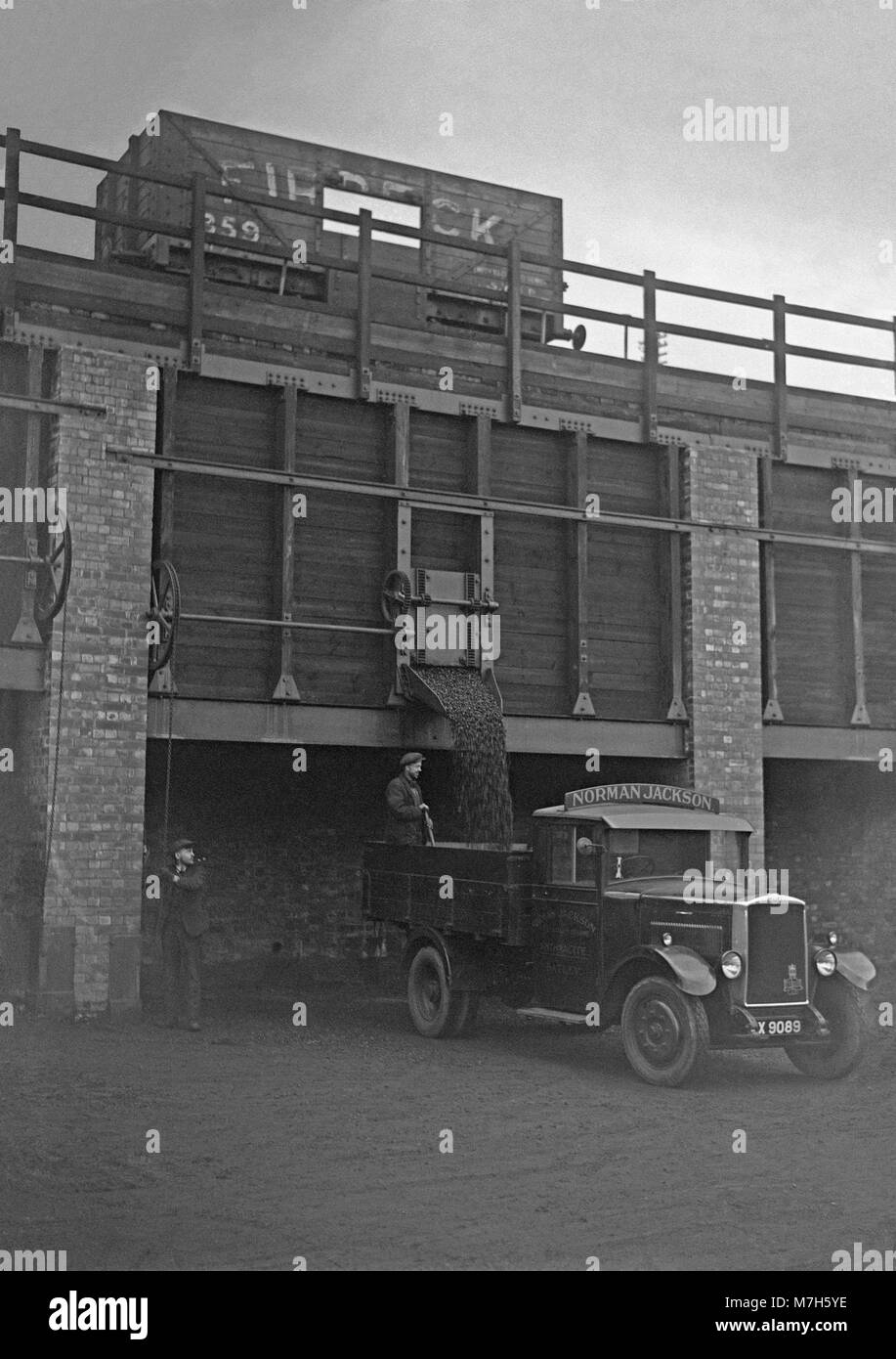 Le charbon d'être chargés à bord d'un camion de livraison via une chute verticale, charbon (staithe ou shute) directement à partir d'un wagon de chemin de fer au-dessus c. 1950. Il s'agissait d'une vision commune à embranchements ferroviaires lorsque le charbon a été utilisé comme le principal élément de chauffage domestique après la Seconde Guerre mondiale - celui-ci était situé près de Leeds, West Yorkshire, England, UK Banque D'Images