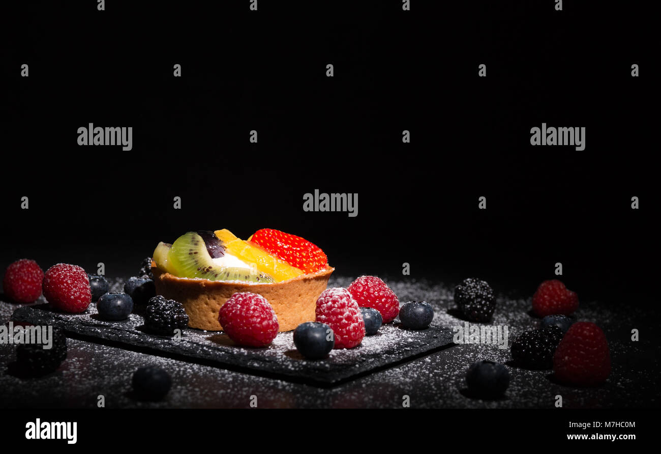 Gâteau aux fruits faits maison fraîchement préparés sur une table sous un spot light. Banque D'Images